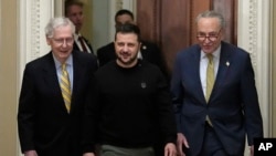 Prezidan Ikrenyen Volodymyr Zelenskyy (mitan) mache ak Lide Majorite Sena Ameriken an, Chuck Schumer (a dwat - Demokrat Nouyok) epi Mitch McConnell (a goch - Repibliken Kentucky) , nan Kongre a nan Washington, 12 Desanm, 2023. 