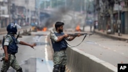 ڈھاکہ، بنگلہ دیش میں، وزیر اعظم شیخ حسینہ اور ان کی حکومت کے خلاف مظاہروں میں نافذ کرفیو کے دوران ایک پولیس اہلکار گن کو تاک کر مظاہرین پر نشانہ لگا رہا ہے۔ 5، اگست 2024۔فوٹو اے پی