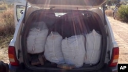 FILE - This photo released by Mexico's National Security Commission shows bags of illegal drugs, including 100 pounds (45.5 kilograms) of fentanyl, inside a sports utility vehicle Ensenada, Baja California, Mexico, Jan. 25, 2018. 