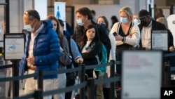 FILE - Passengers wait in line at the security checkpoint at Ronald Reagan Washington National Airport, April 19, 2022, in Arlington, Va. 