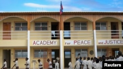 Children walk across the schoolyard of the Academy for Peace and Justice, run by a Catholic priest, in Port-au-Prince January 9, 2012. Bankrolled by a roster of Hollywood celebrities, the Academy of Peace and Justice is Haiti's first free secondary school