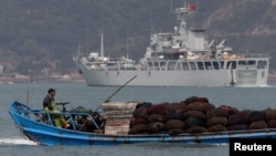 Bir balıkçı teknesi, Tayvan kontrolündeki Matsu Adaları'nın karşısında, Fuzhou yakınlarındaki Çin kıyılarında yapılan bir askeri tatbikat sırasında bir Çin savaş gemisinin yanından geçiyor- 11 Nisan 2023.