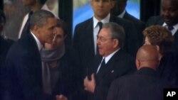 Hình ảnh chụp từ truyền hình cho thấy Tổng thống Mỹ Barack Obama bắt tay Chủ tịch Cuba Raul Castro tại Sân vận động FNB ở Soweto, Nam Phi.