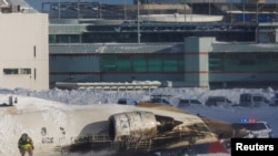 An emergency responder works around an aircraft on a runway after a plane crash at Toronto Pearson International Airport in Mississauga, Ontario, Canada, Feb. 17, 2025.