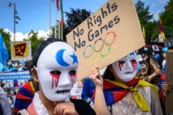 Tibetan and Uyghur activists hold placards and wear masks during a protest against Beijing 2022