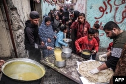 رفح میں پناہ لینے والے بے گھر فلسطینی ماہ رمضان میں افطار کے لیے ایک امدادی گروپ کی جانب سے تقسیم کیا جانے والا کھانا حاصل کرنے کے لیے اپنی باری کا انتظار کر رہے ہیں۔ 16 مارچ 2024