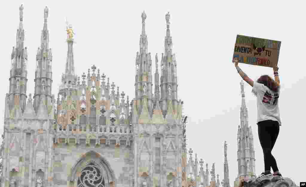 A girl holds up a card with writing reading in Italian &quot;Lets photosynthesize, also you become plastic phobic&quot; during a worldwide protest demanding action on climate change in front of Milan&#39;s gothic cathedral, Italy.