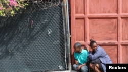 People take cover during clashes between gangs and security forces, in Port-au-Prince