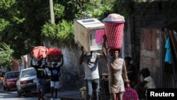 People carry their belongings along a street as they flee their homes from gang violence, in Port-au-Prince, Haiti, Oct. 26, 2024.