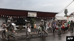 Members of the M23 armed group walk alongside residents through a street of the Keshero neighborhood in Goma, on January 27, 2025.