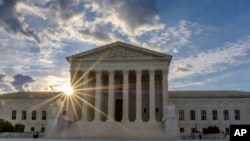 The sun flares in the camera lens as it rises behind the U.S. Supreme Court building in Washington, June 25, 2017.