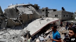 People inspect the rubble of a destroyed residential building which was hit by Israeli airstrikes, in Gaza City, May 12, 2021.