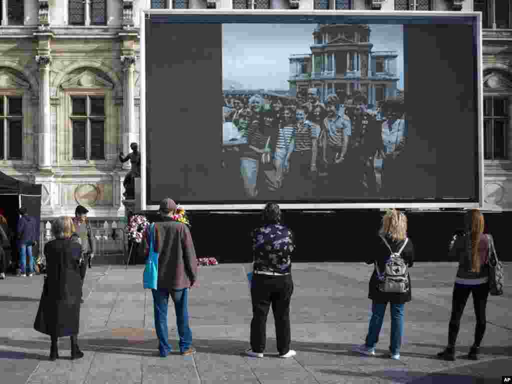 People watch former President Jacques Chirac on a giant screen set up at the Paris town hall Paris.