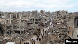 Palestinians walk past the rubble of buildings destroyed during the Israeli offensive, on a rainy day in Gaza City amid a ceasefire between Israel and Hamas, Feb. 6, 2025. 