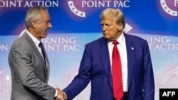 (FILES) Former US President and Republican presidential candidate Donald Trump (2nd L) shakes hands with US politician Robert F. Kennedy Jr. as he invites him former US Representative Tulsi Gabbard (R) and US commentator Tucker Carlson onto the stage duri